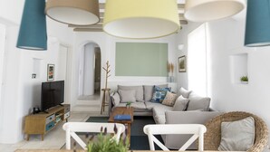 Un salón moderno con sofá, mesa de centro y mueble para la televisión. El suelo es de madera y hay un ventanal grande que proporciona luz natural.