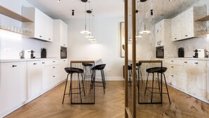 A modern kitchen with white cabinets, black bar stools, and pendant lighting. - Romántico Pied-a-terre en el Centro de Sevilla (Sevilla)