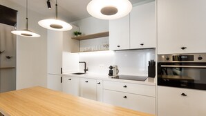 A modern kitchen with white cabinets, a wooden countertop, pendant lights, and built-in appliances. - Romántico Pied-a-terre en el Centro de Sevilla (Sevilla)