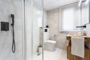 Et moderne badeværelse med en glasbrusekabine, toilet og et underskab med et håndklæde hængende på siden.