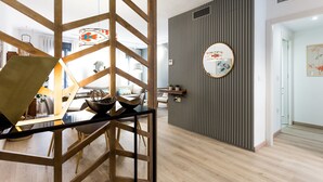 A modern interior with a dining area, a wall-mounted mirror, and a wooden floor. - Spacious and luxurious designer apartment in the heart of Seville (Sevilla)