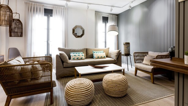 A modern living room with a sofa, coffee table, wicker chairs, and a patterned rug. - Spacious and luxurious designer apartment in the heart of Seville (Sevilla)