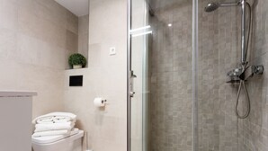 A modern bathroom with a glass-enclosed shower, a toilet, and a small potted plant on the wall. - Spacious and luxurious designer apartment in the heart of Seville (Sevilla)