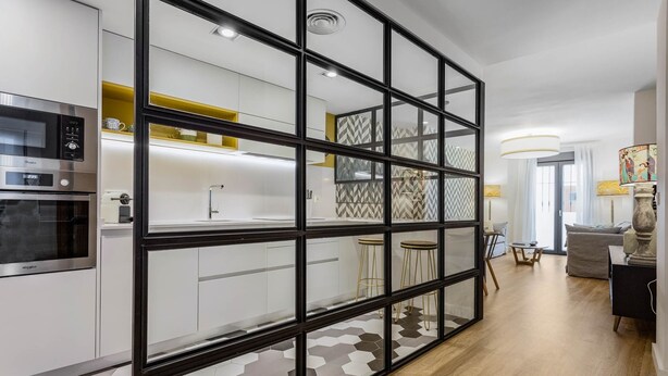 A modern kitchen with built-in appliances, a glass partition, and a hexagonal tile floor. - Design apartment next to La Maestranza & Cathedral (Sevilla)