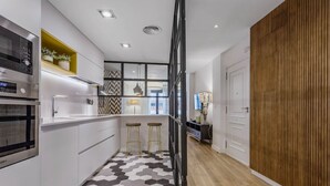 A modern kitchen with a hexagonal tile floor, a built-in oven, and a countertop with stools. - Design apartment next to La Maestranza & Cathedral (Sevilla)