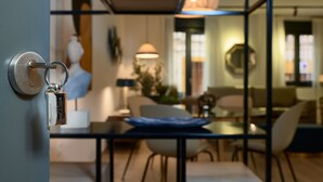 Un interior moderno con una cerradura metálica, una mesa de comedor con sillas y una sala de estar con sofá y lámpara.