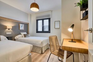 A hotel room with two beds, a desk, a chair, a lamp, a window, and a wall-mounted shelf with plants. - Modernity & luxury a few steps from everything in Seville (Sevilla)