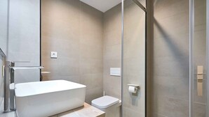 Un baño moderno con una bañera independiente, un inodoro y un box de ducha de vidrio.