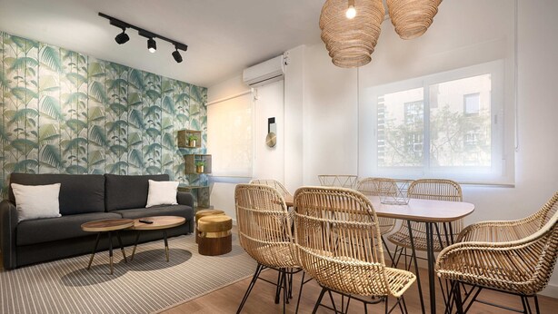 A modern living room with a sofa, round coffee table, wicker chairs, and a dining table. - Amador de los Rios Free Parking Gratis (Sevilla)