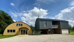 Ein modernes Haus mit einer geschwungenen Ziegelstruktur und einem Anbau aus Metall.