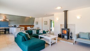 Ein modernes Wohnzimmer mit einem grünen Sofa, einem weißen Couchtisch und einem Kaminofen.