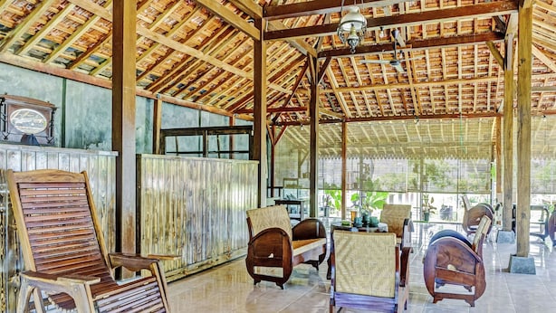 A spacious room with a high wooden ceiling, large windows, and several wooden chairs and tables. - SPOT ON 90742 Kinanthy Homestay Syariah (Tulungagung)
