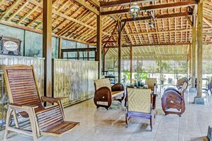 Una habitación amplia con techo de madera alto, ventanas grandes y varias sillas y mesas de madera.