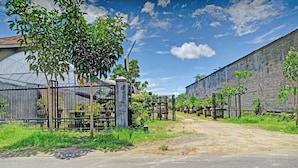 A gated area with a greenhouse, a dirt path, and a brick wall. - SPOT ON 90742 Kinanthy Homestay Syariah (Tulungagung)