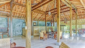 A spacious room with a high wooden ceiling, tiled floor, and several wooden chairs and tables. - SPOT ON 90742 Kinanthy Homestay Syariah (Tulungagung)