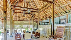 A covered outdoor seating area with wooden furniture and a tiled floor. - SPOT ON 90742 Kinanthy Homestay Syariah (Tulungagung)