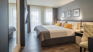 Une chambre d’hôtel moderne dotée d’un grand lit, d’un coin salon et offrant une vue sur l’extérieur.