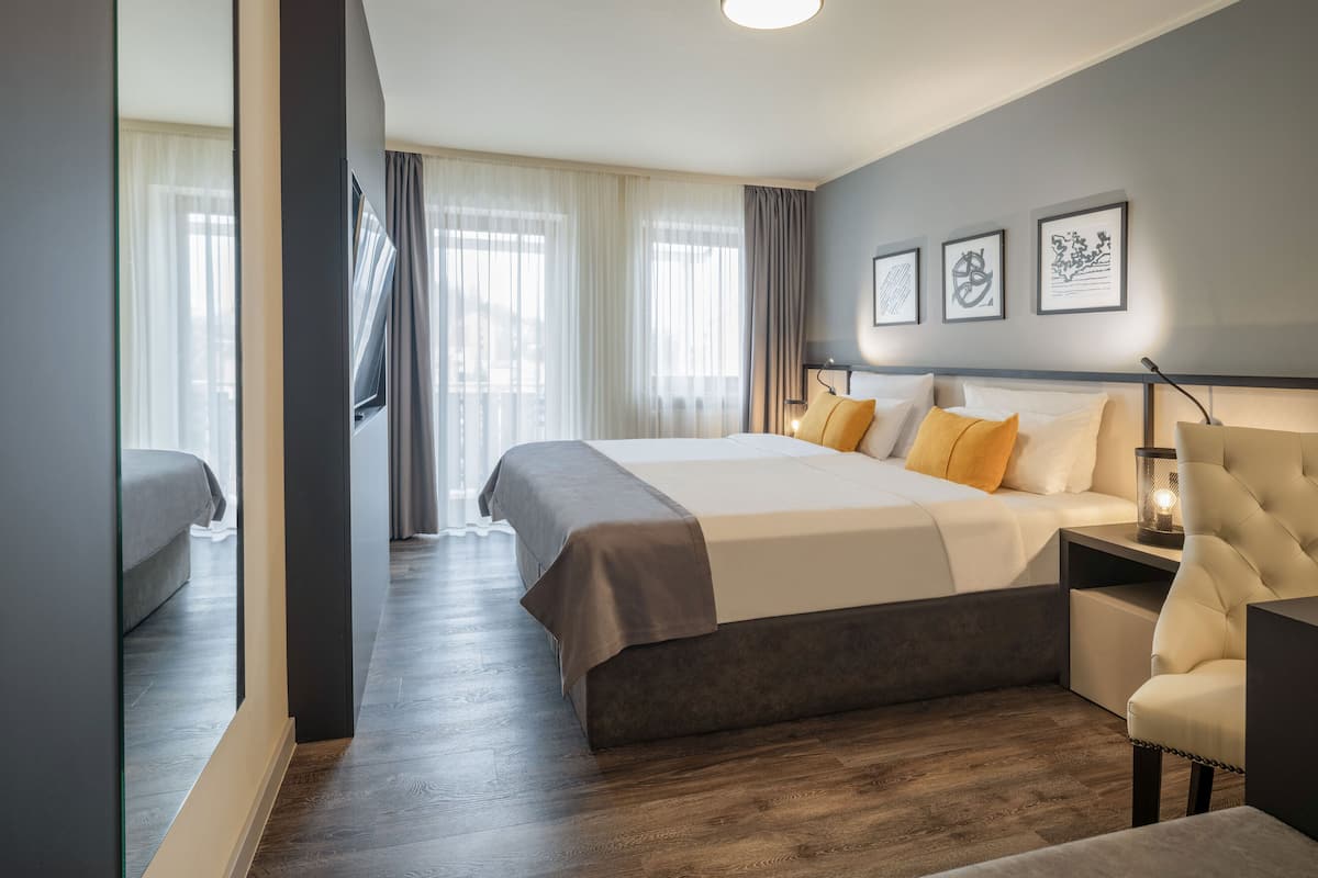 Une chambre d’hôtel moderne dotée d’un grand lit, d’un coin salon et offrant une vue sur l’extérieur.