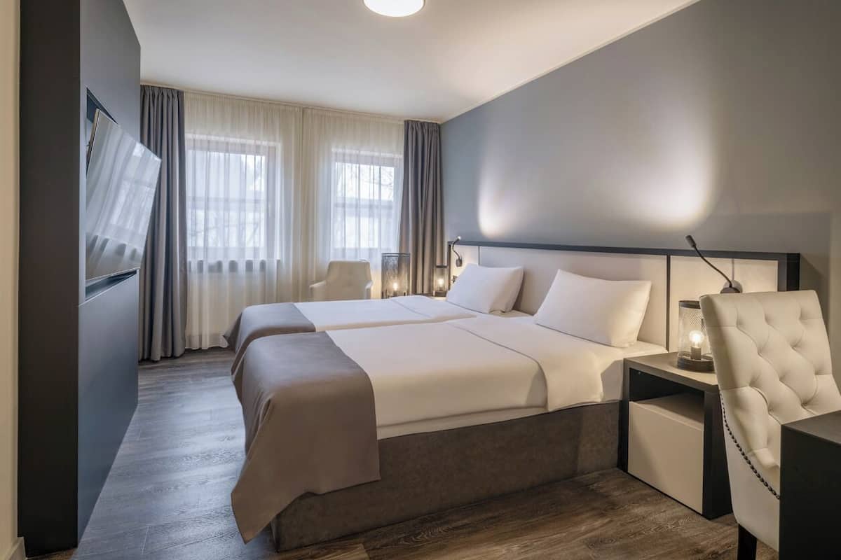 Une chambre d’hôtel moderne, dotée d’un grand lit, de tables de chevet, d’une chaise et d’un téléviseur.
