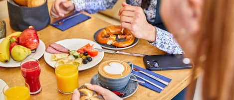 A breakfast setting with various food items, drinks, and a smartphone on the table.