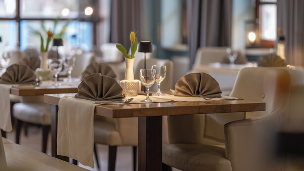 Un restaurant où les tables sont dressées pour le service, avec un décor intérieur moderne aux tons neutres et une présentation élégante.