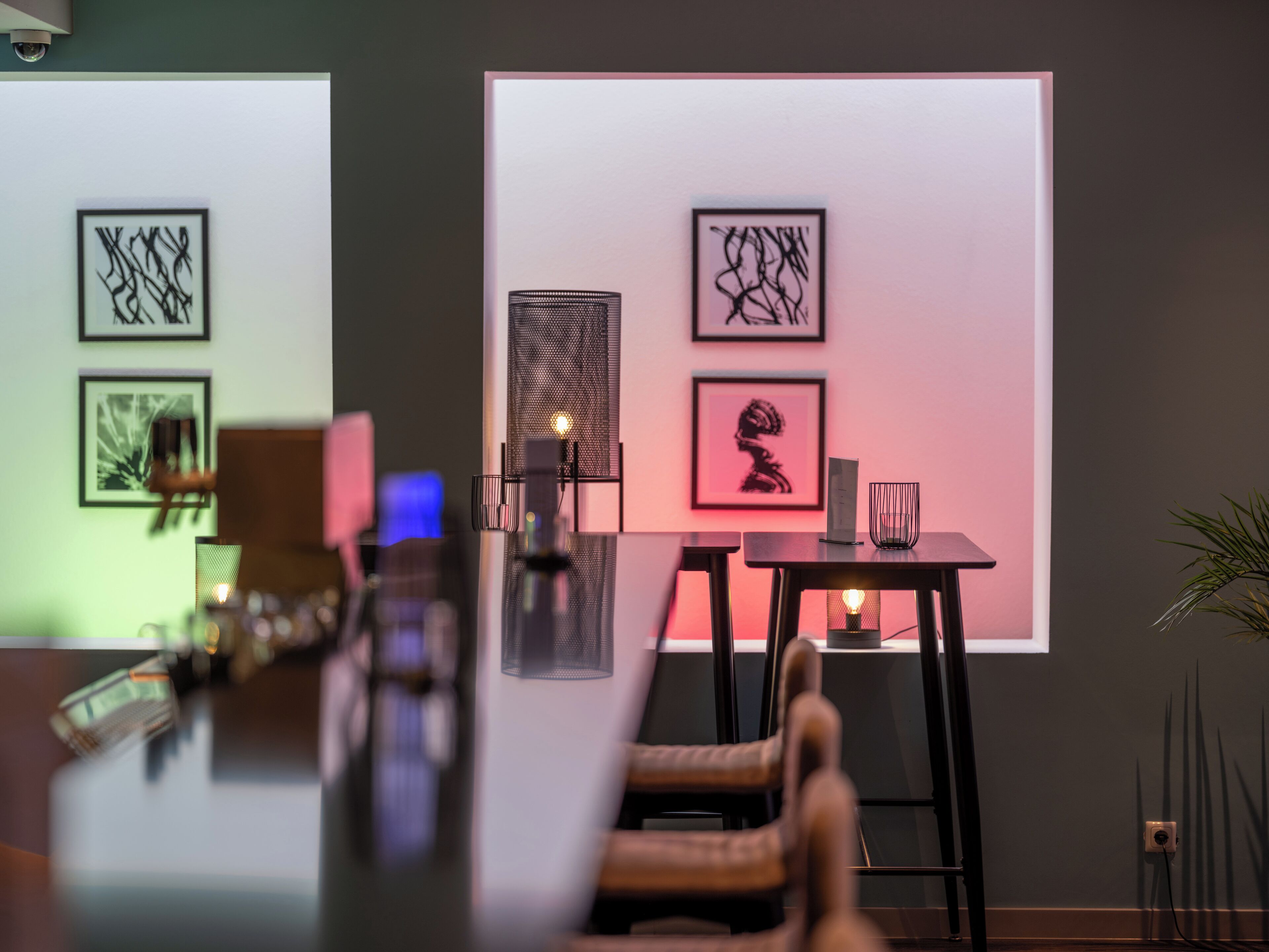 A modern interior with a dining area featuring a table and chairs, framed artwork on the walls, and a potted plant.