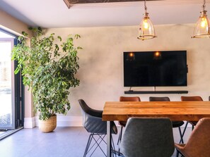 Un comedor con una planta grande, una mesa de madera y dos lámparas colgantes.