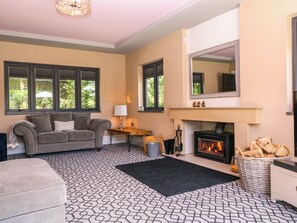 A living room with a fireplace, a sofa, a coffee table, and a patterned rug. - Thornbury (Malvern)
