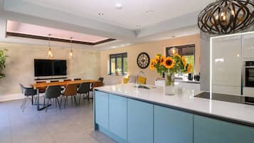 Cocina moderna con una isla central, comedor con sillas, televisor de pantalla plana en la pared y un ventanal con vistas.