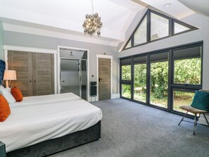 Un dormitorio con cama, vestidor, ducha y ventanas amplias.