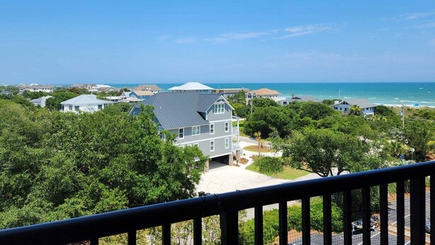 A residential area with houses, a clear blue sky, and a view of the ocean. - Beautiful 6th floor, cathedral ceiling, ocean view condo (Pawleys Island)