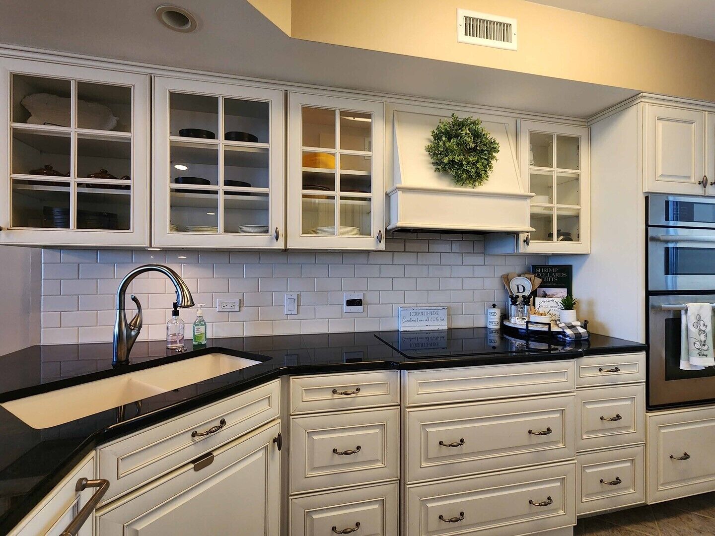 A kitchen with white cabinetry, a black countertop, and a stainless steel oven.