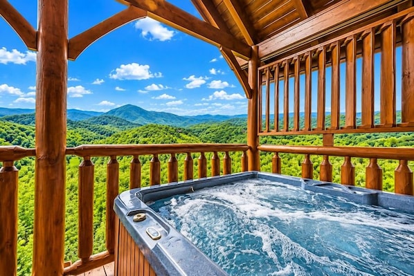 A hot tub on a wooden deck with a view of a mountainous landscape.
