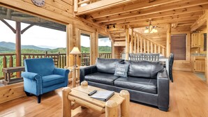 A wooden cabin interior with a blue armchair, black leather sofa, and a wooden coffee table. - Aurora, Free Tickets, Breathtaking Views, “Cozy Cabin Retreat in the Smokies!!! (Sevierville)