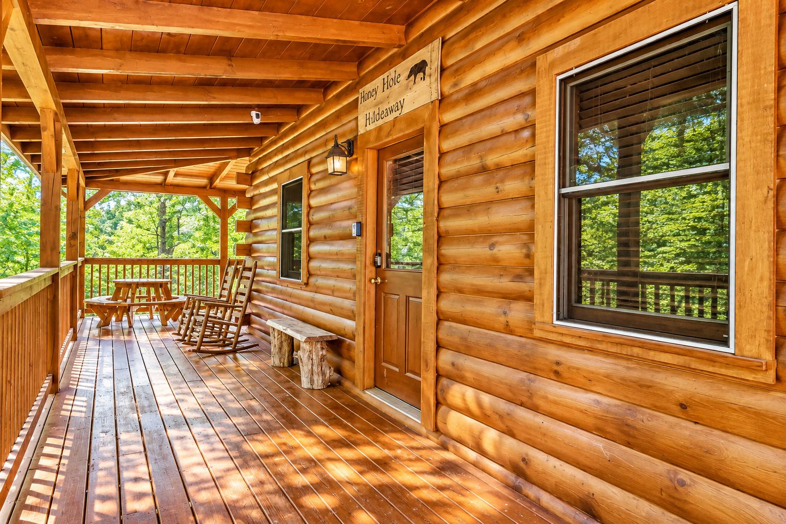 Una cabaña de madera con un porche, un letrero que dice 'Honey Hole Huleaway', y vistas al bosque.