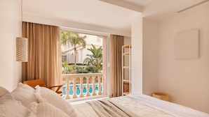 A hotel room with a bed, a window with curtains, a view of a pool and greenery, and a white wall with a picture frame. - Maison Carla Rosa (Cannes)
