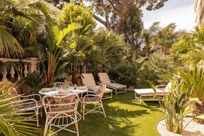 A garden patio with a round table, wicker chairs, and a sun lounger. - Maison Carla Rosa (Cannes)