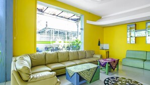 A living room with a beige sofa, a coffee table, and a patterned rug. - OYO 90863 Omah Kost Syariah (Tulungagung)
