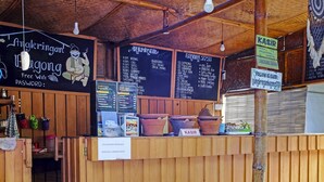 A rustic wooden counter with a chalkboard menu listing various food items. There are terracotta pots on the counter, and a sign indicating 'Free WiFi'. - OYO 90863 Omah Kost Syariah (Tulungagung)