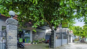A building with a stone pillar, a motorcycle parked outside, and a signboard. - OYO 90863 Omah Kost Syariah (Tulungagung)