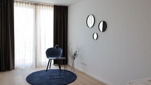 Une pièce moderne avec un tapis rond bleu, un fauteuil bleu foncé et trois miroirs fixés au mur.