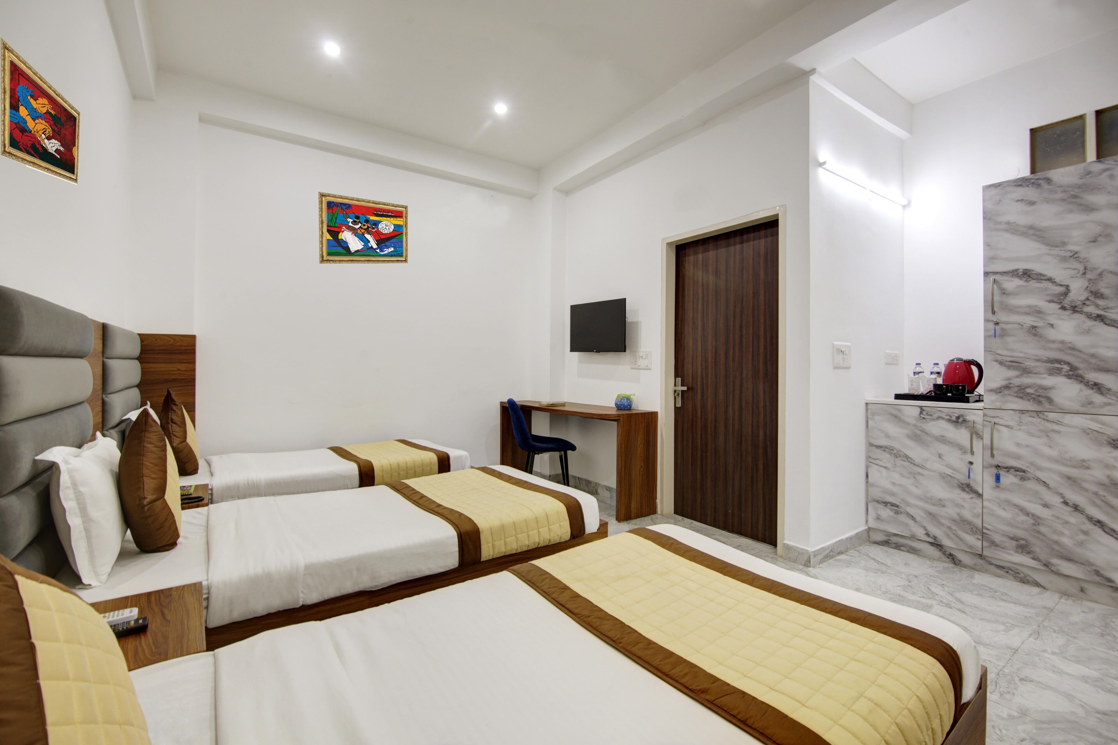 A hotel room with two beds, a desk, a TV, a wardrobe, and a marble wall.