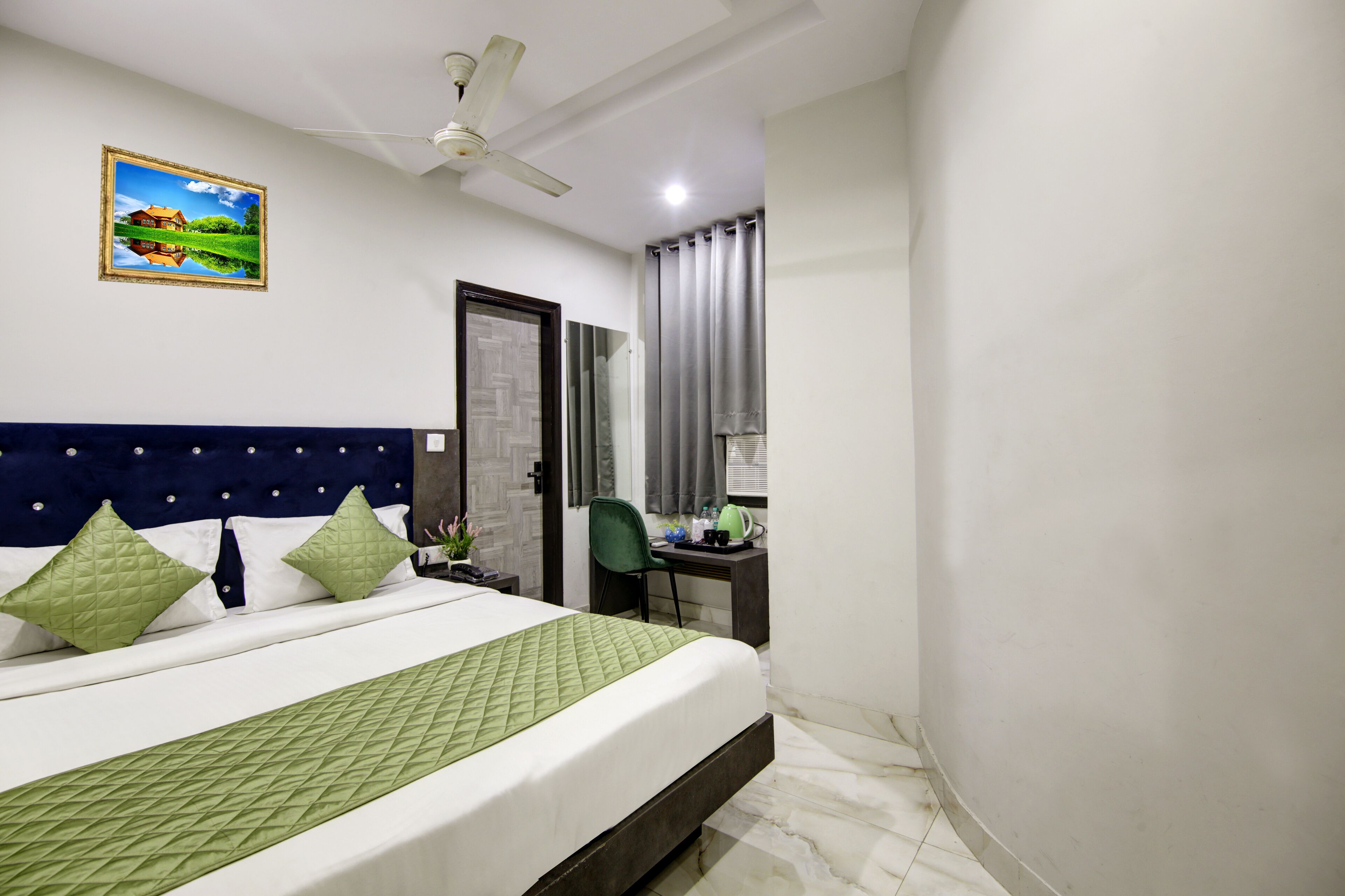 A bedroom with a bed, a desk, a chair, a ceiling fan, and a door.