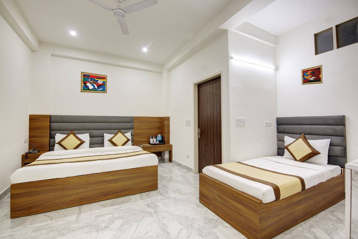 A hotel room with two beds, a wooden headboard, a bedside table with a phone, and a nightstand.
