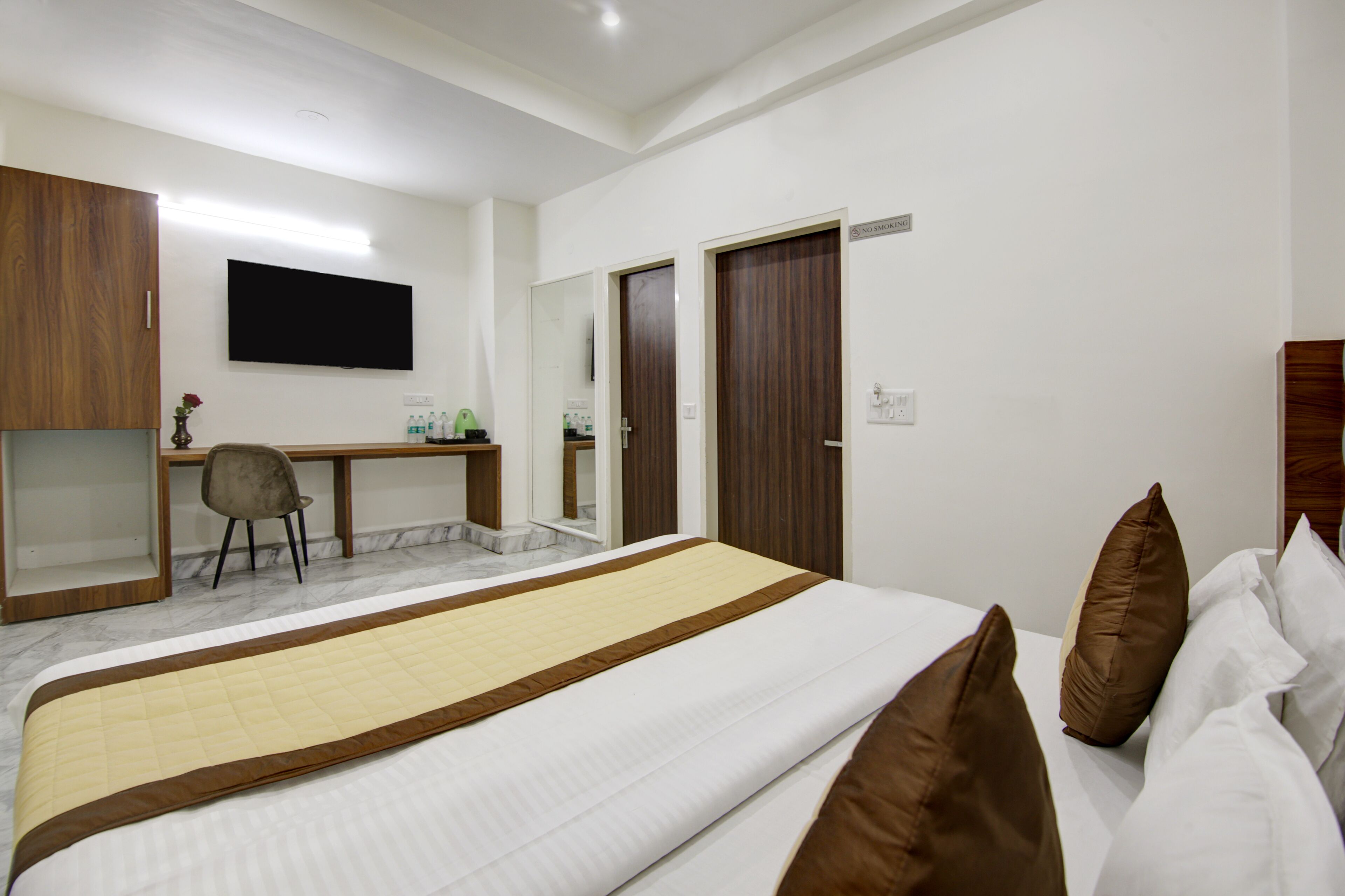 A hotel room with a bed, a desk, a chair, and a television.