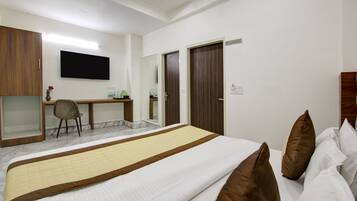 A hotel room with a bed, a desk, a chair, and a television.