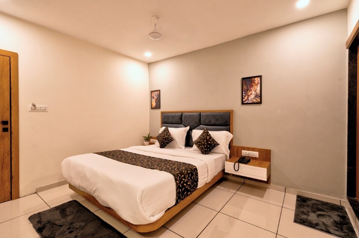 A modern bedroom with a large bed, a bedside table with a phone, and a small bedside plant.