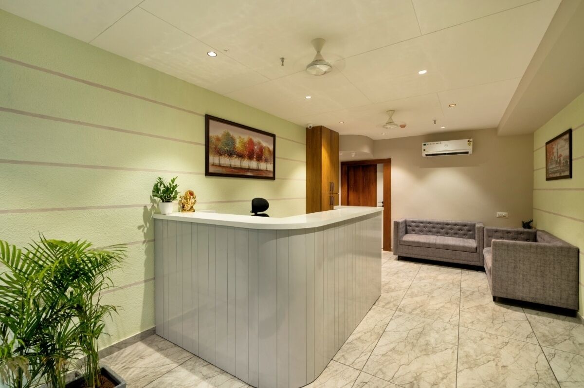 A reception area with a curved reception desk, a sofa, and a potted plant.