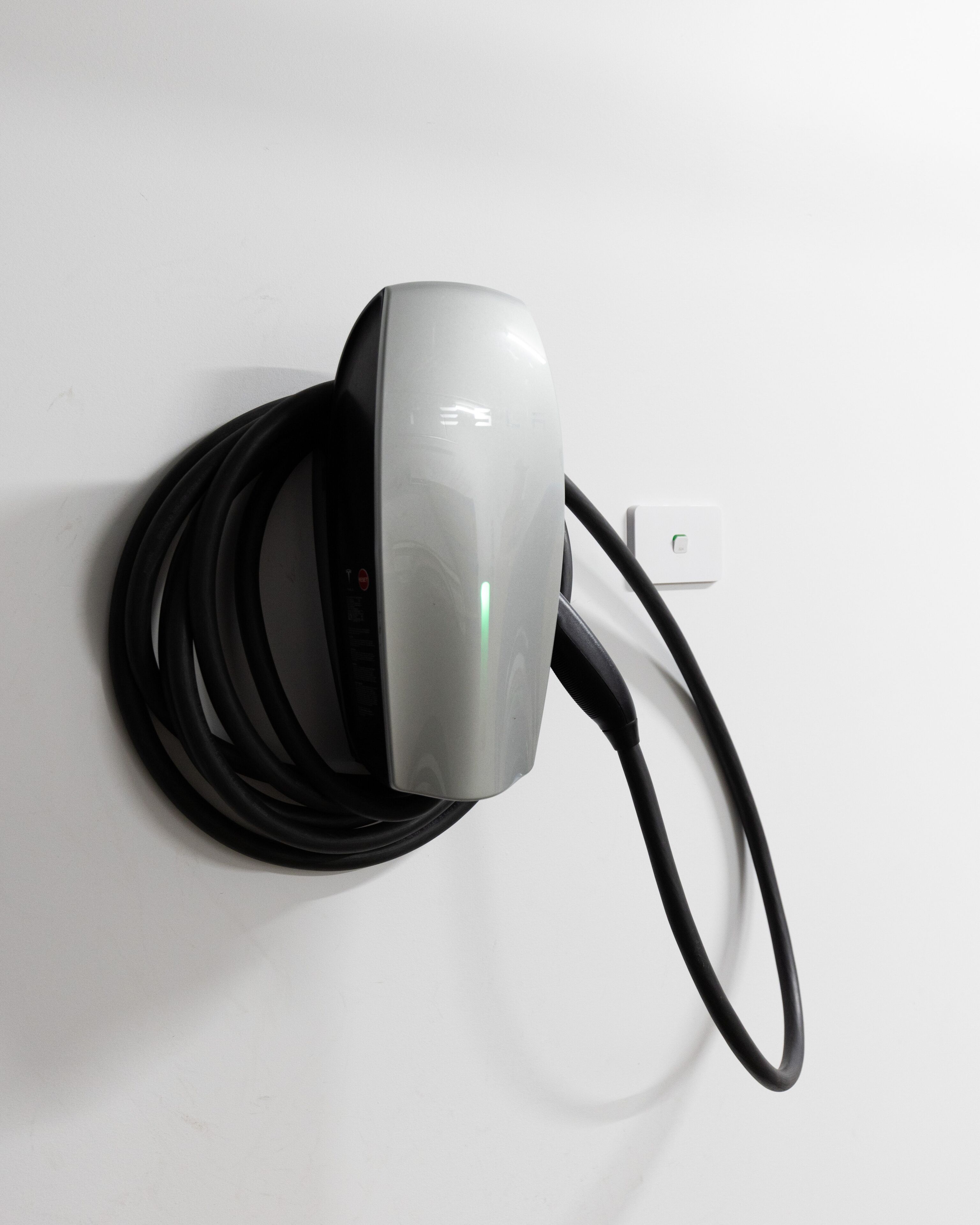 Een wandmontage oplaadstation met een kabel eromheen gewikkeld.