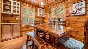 A wooden interior with a dining table, benches, and cabinets. - Peaceful 3BR GBurg w/Hot Tub + Fireplace* Privacy! (Sevierville)